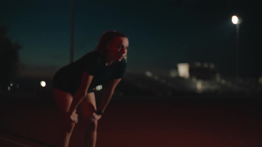Female athlete runs on track at night
