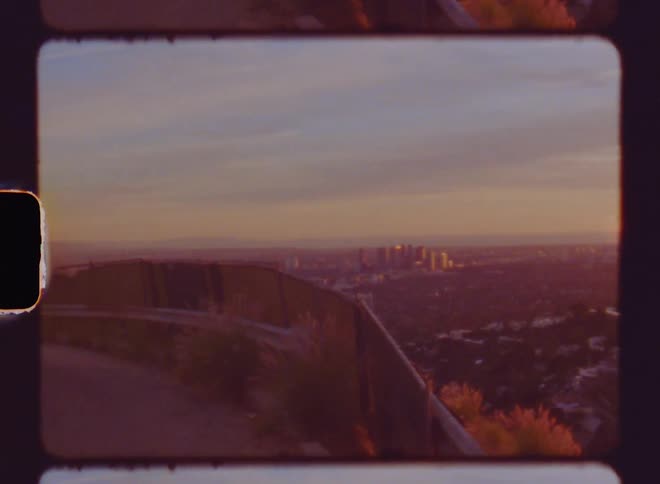 The view of a city skyline at sunset as seen from a road with guardrails