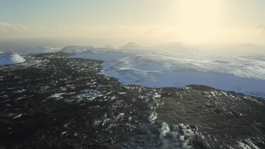Black lava ground and snow by the sea
