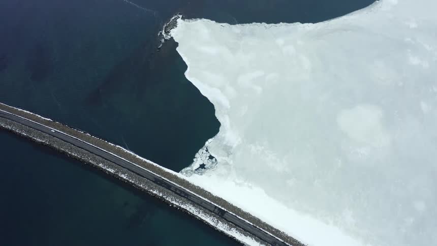 A vehicle drives past the frozen water