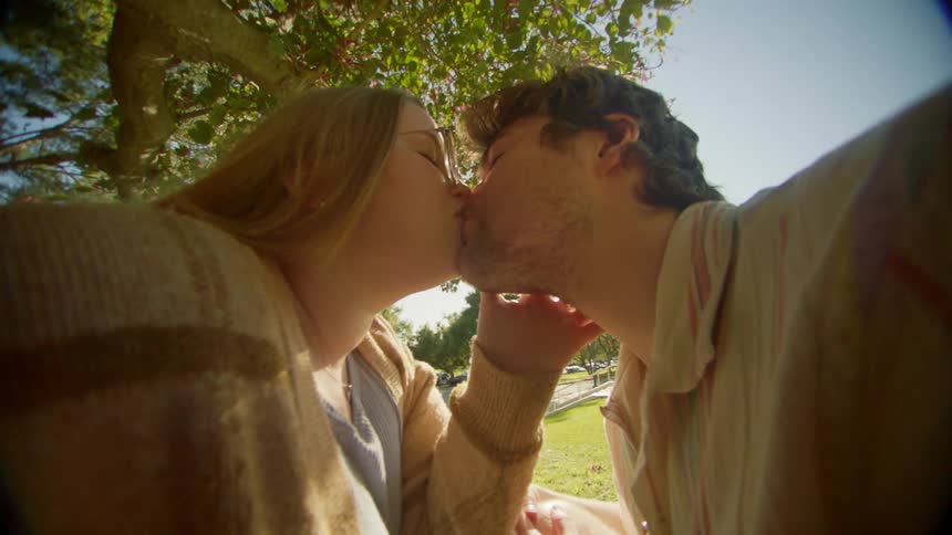 A man and a woman kiss in a park