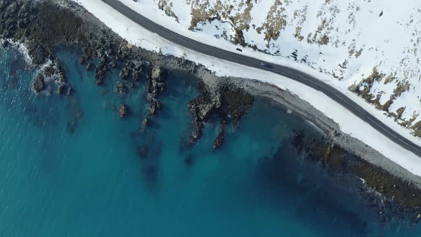 A car drives on a road directly on a coast