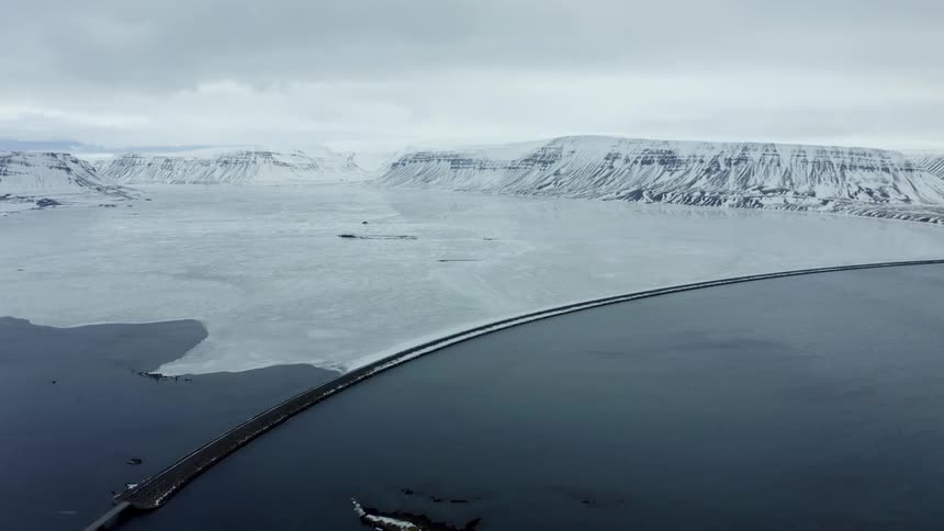 Aerial view of a frozen coastline near snow covered mountains