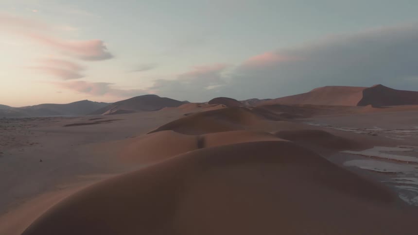Ice forms patches in the desert under red tinted clouds