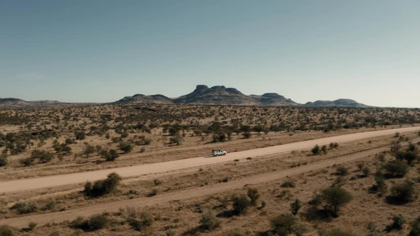 A vehicle is driving down the dirt road in the desert