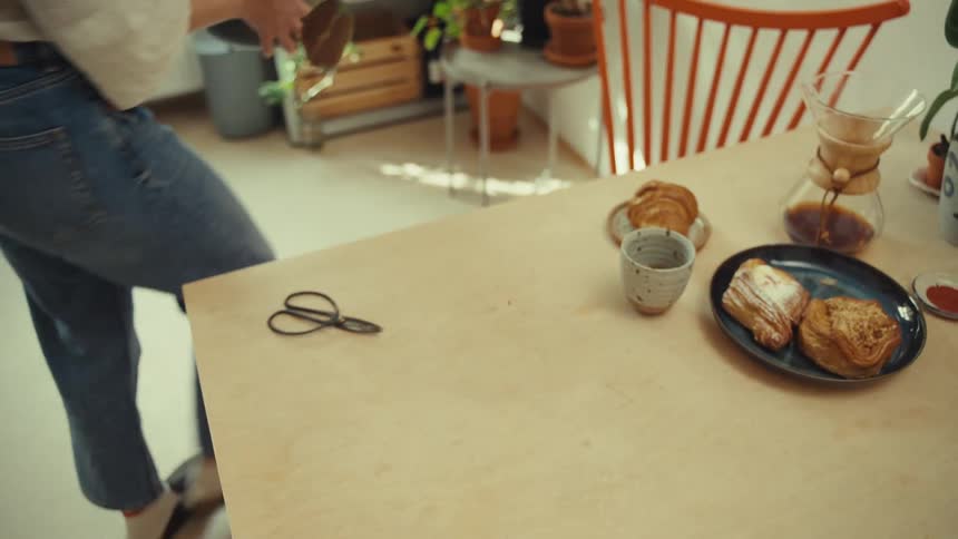 A woman tending house plants at home during breakfast