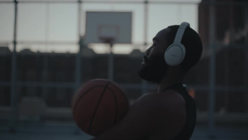 Man with headphones walking on a court with a basketball