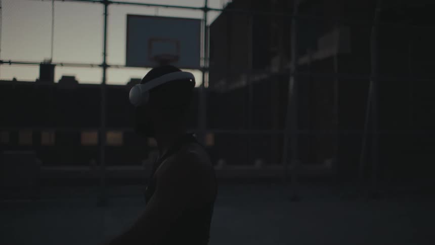 Silhouette of a man walking backwards on a basketball court and using headphones