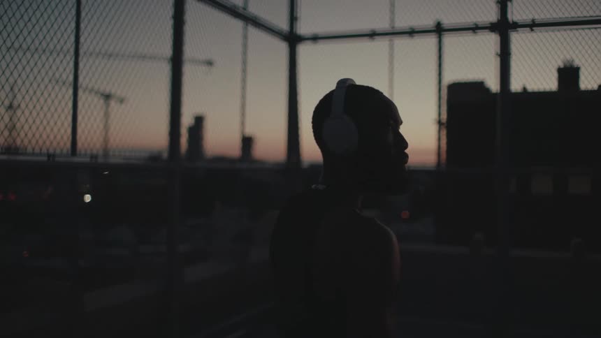 A black man wearing headphones looks around