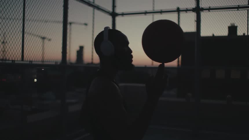A black man spins a basketball on his finger