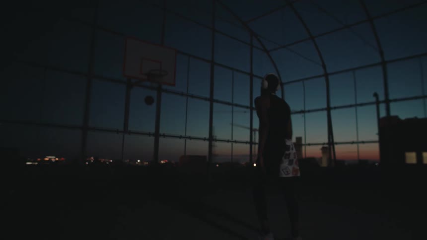 A black man shoots a basketball in an enclosed court