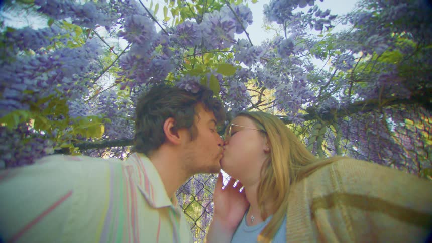 Man and woman are making out under a lavender tree near fences