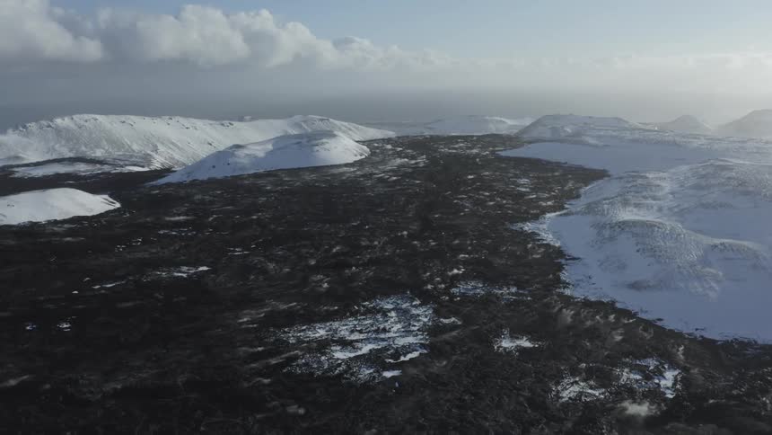 Aerial view of a snowy landscape with dark terrain and patches of snow
