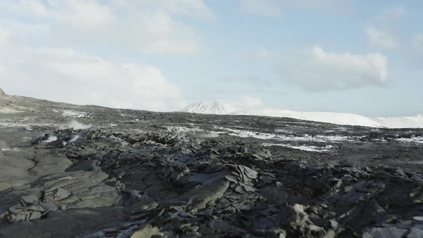 Smoke rises from fissures in a massive lava field