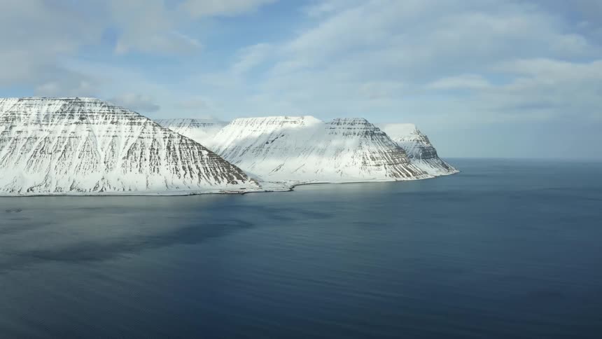 Two huge snowcapped mountains on the left in contrast to the blue ocean