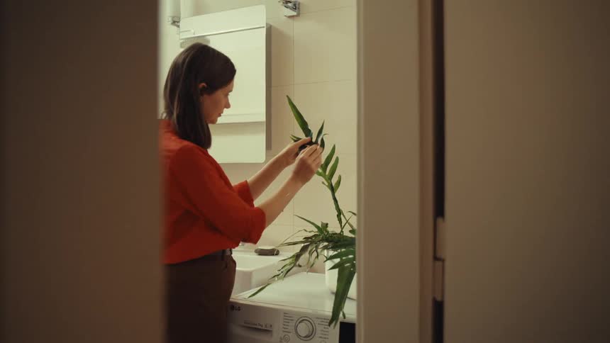 A woman tending a plant in the utility room at home