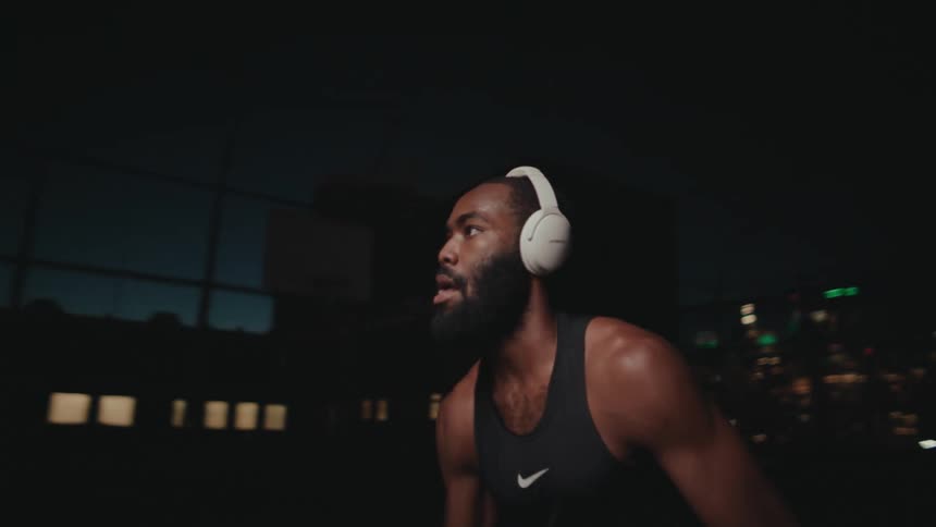 A black man dribbles a basketball on an enclosed court