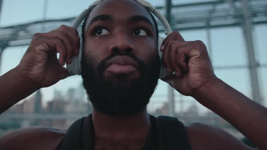 A black man puts headphones on