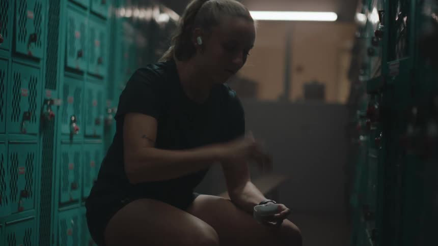A woman puts in her earbuds in the locker room