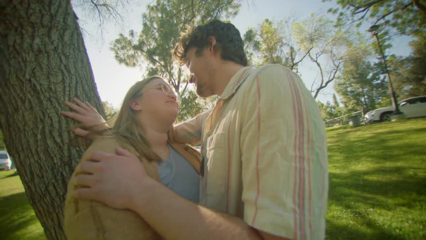 Couple looking at each other romantically while standing in a garden next to a tree
