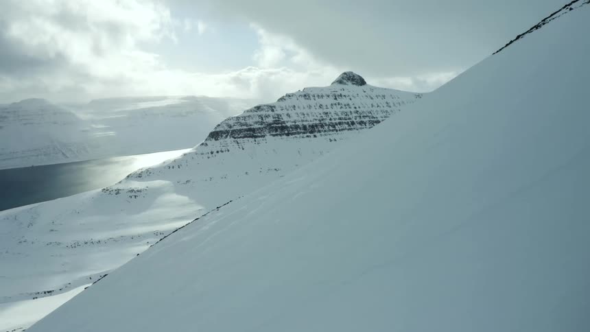 Aerial aerial scenery of snowy mountains on the edge of a river bank