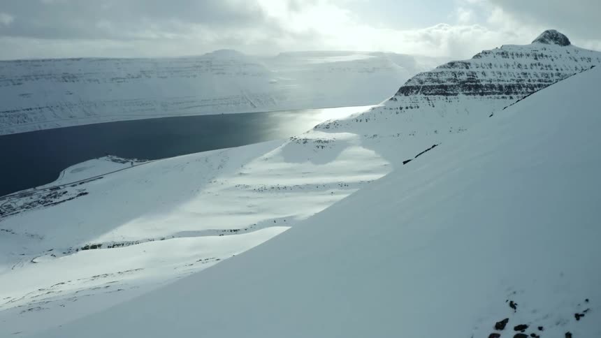 Landscape of snowcovered mountain ranges and a river on the bank