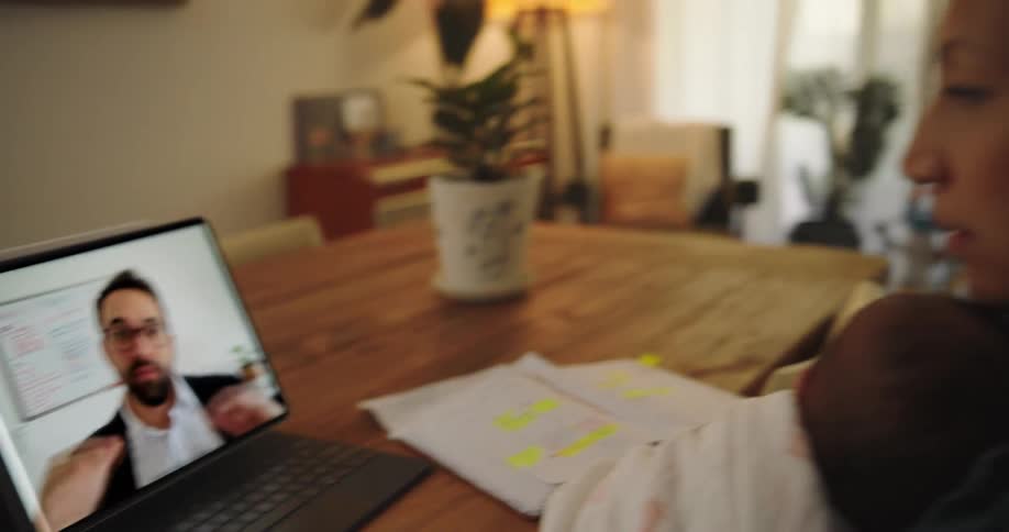 Mother holding her baby in her lap while studying and taking notes with a pen