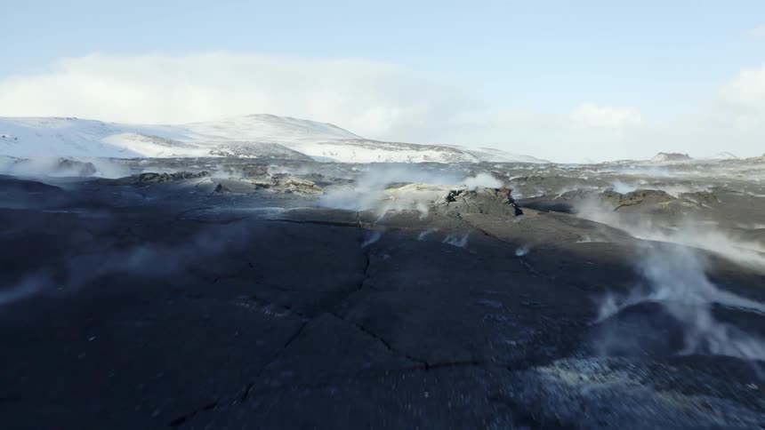 Landscape of rocks and craters with erosions and mountains with snow around