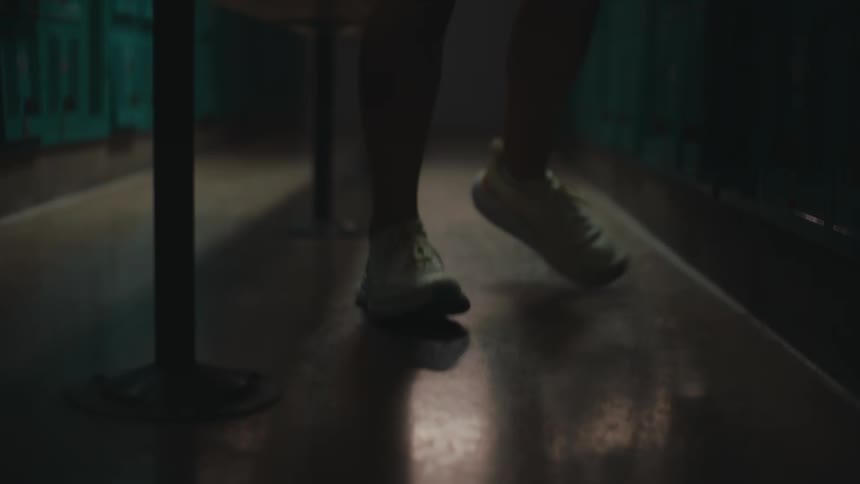 Legs of a person who is walking in a place full of blue lockers