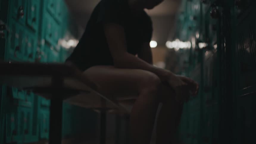 A woman is listening to earbuds in the locker room