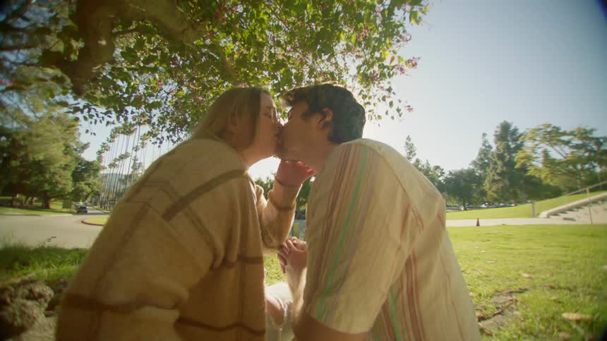 A man and woman share a romantic kiss in a park