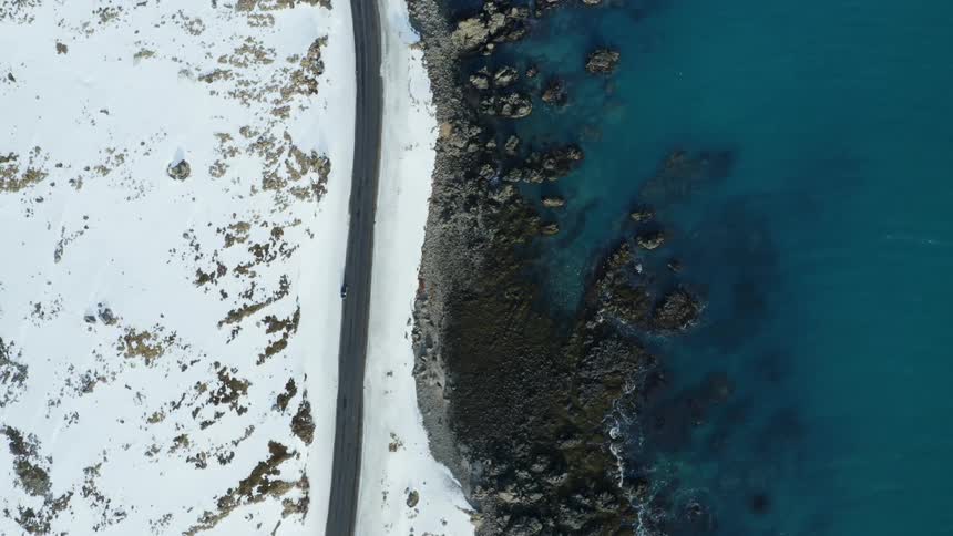 Aerial view of a coastal road in a snowy field by the sea