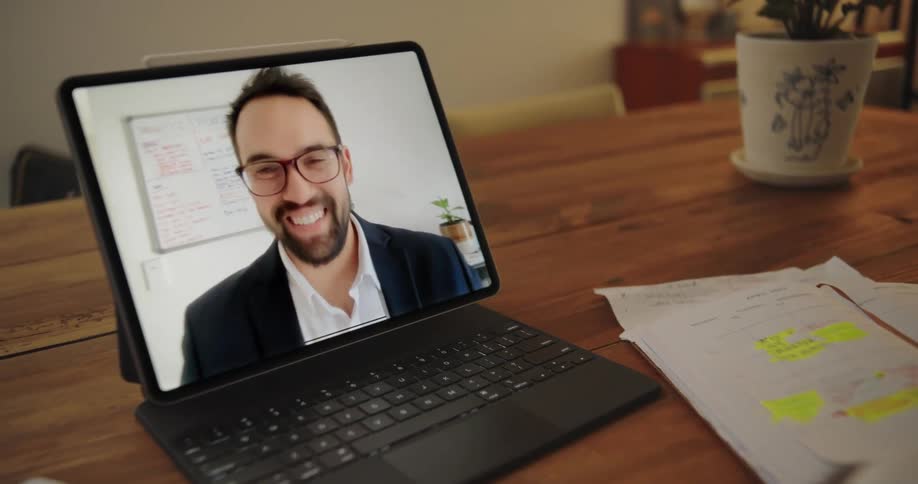 Man on screen waves at person working from home during a video call