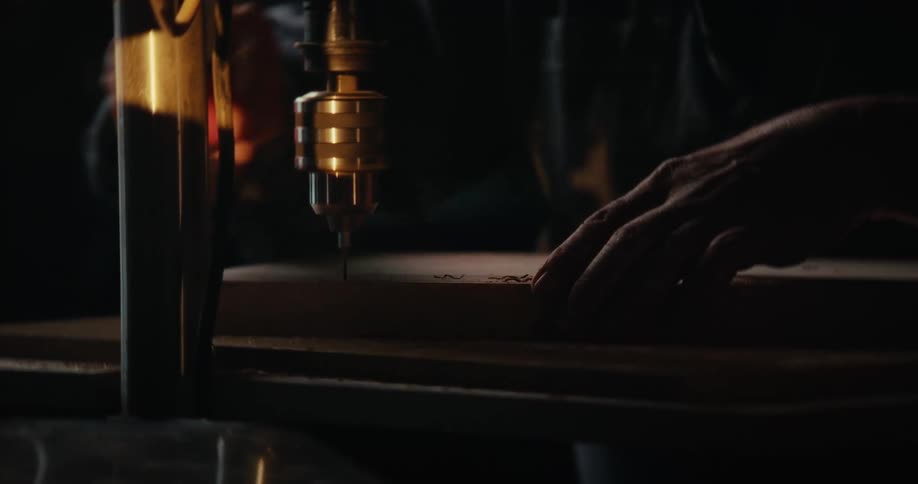 Hands of a carpenter with the help of a machine drilling holes in wood