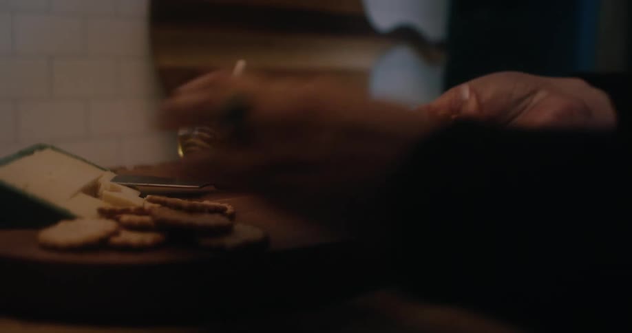 Womans hands preparing cheese and cold cuts presentation on a rustic wooden board