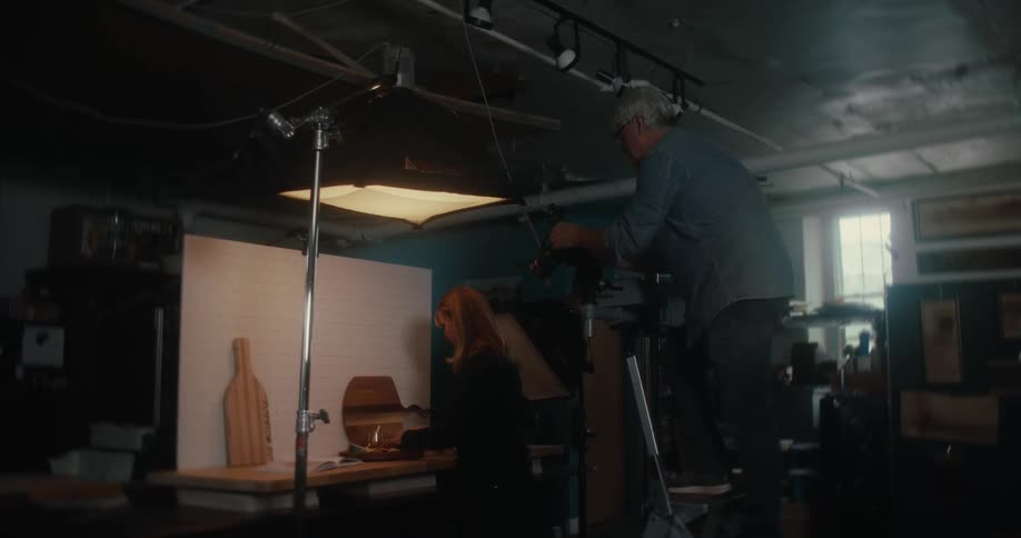 A man watches a younger woman organize items on a desk