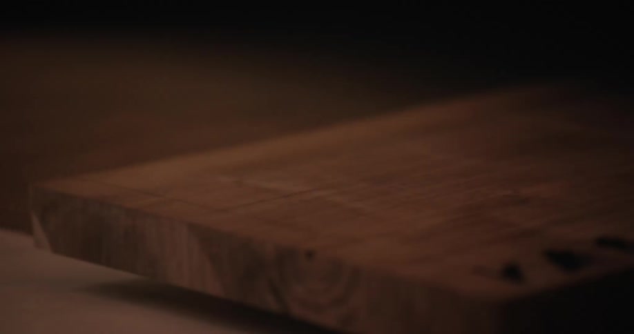 A man grabs a piece of wood from a conveyor