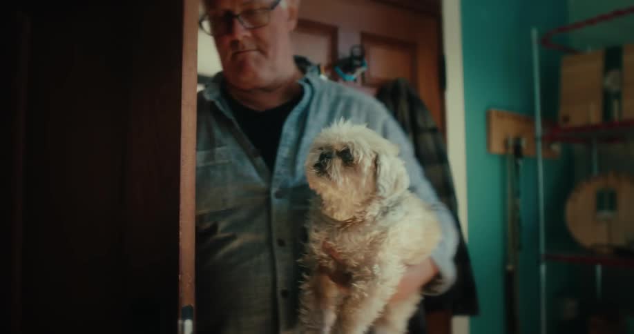 Man entering the house carrying his dog on his arm