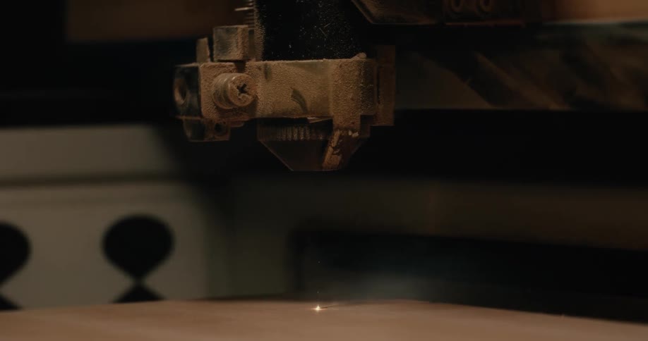 A laser engraver machine cuts a design on a piece of wood