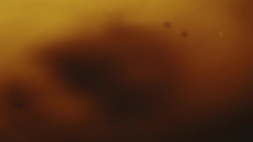 Closeup on a dense golden liquid swirling abstractly