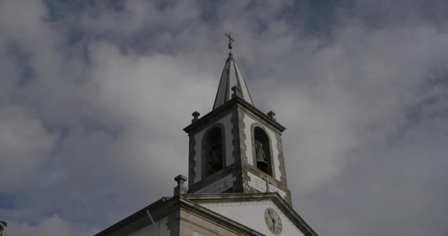 Tower of a church with bell against a blue sky with clouds
