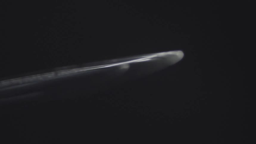 A black circular object is rotating against a completely black background