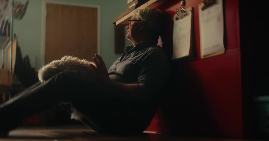 Man sitting on the floor with his dog on his lap petting him