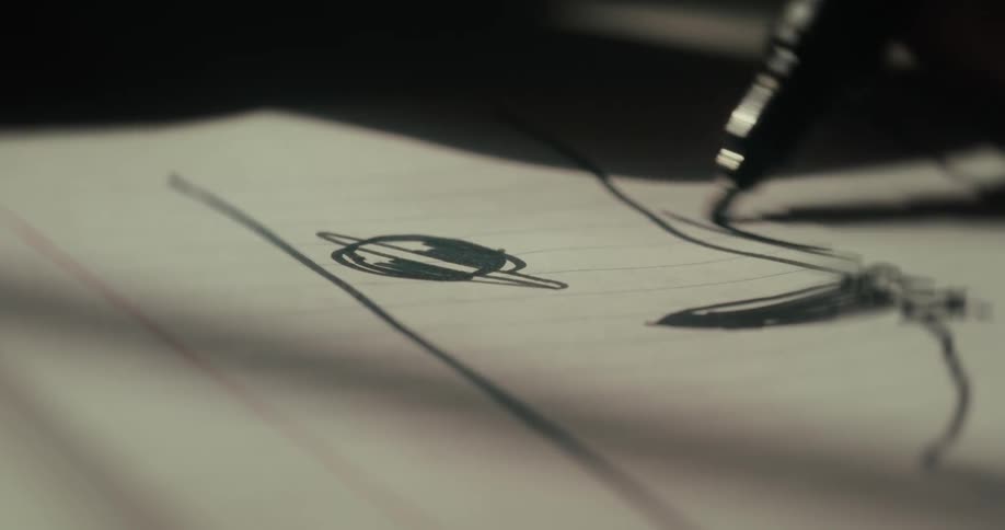 Hand holding a pen and drawing on paper