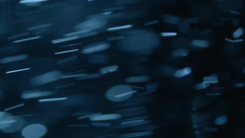 Several blue particles are moving quickly on a black background