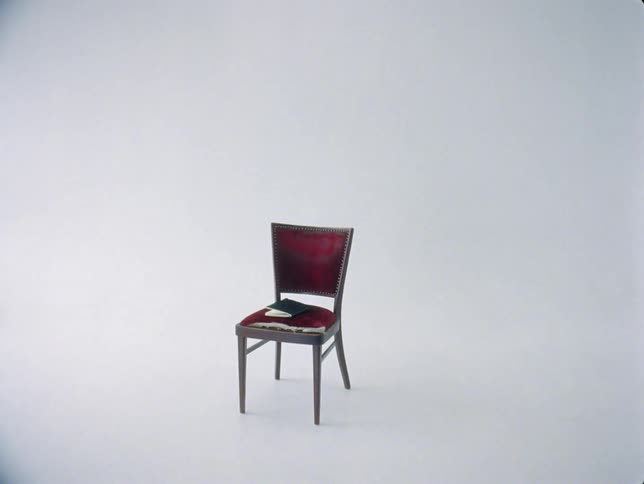 An old chair with a torn fabric seat and a notebook on it in a photo studio