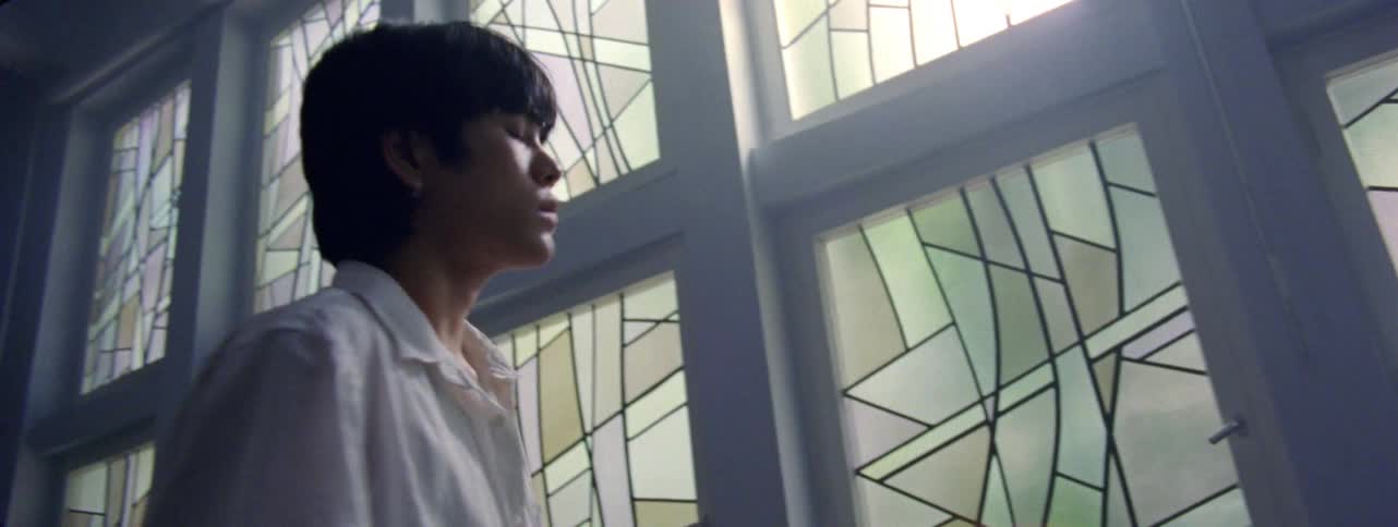 Man indoors with artistic windows that reflect sunlight