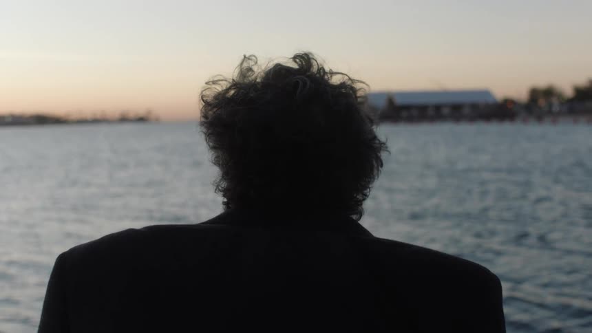 Silhouette of a man looking at the ocean at sunset