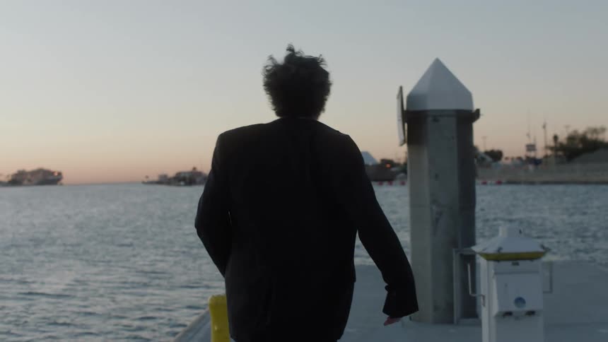 Man runs toward the end of the dock against a red tinted horizon
