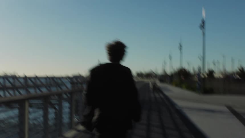 Back view of a man running on a seaside sidewalk